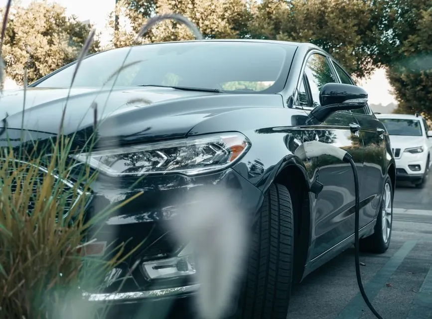 Voiture hybride rechargeable branchée sur une borne à domicile, conducteur consultant sa consommation